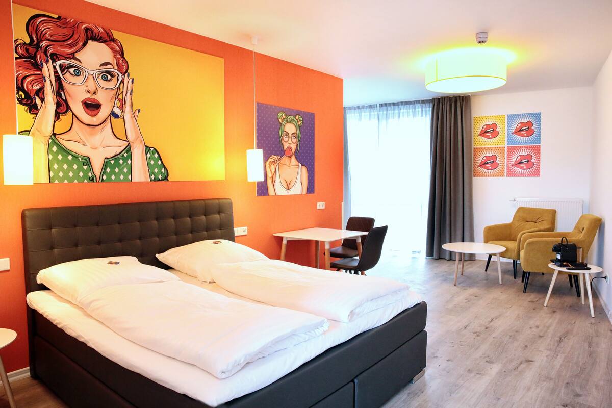 Ein Hotelzimmer mit einem großen Bett, einem Schreibtisch, zwei Stühlen und einem kleinen Tisch.