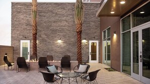 An outdoor patio with a fire feature, seating, and a stone wall. - Courtyard by Marriott Mesa At Wrigleyville West (Mesa)