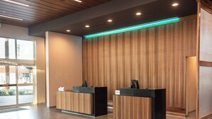 A reception area with two black reception desks, wooden paneling on the wall, and a glass door entrance. - Courtyard by Marriott Mesa At Wrigleyville West (Mesa)