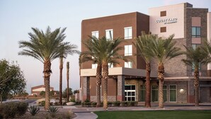 A modern hotel with a courtyard, palm trees, and a clear sky. - Courtyard by Marriott Mesa At Wrigleyville West (Mesa)