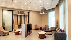 A modern living room with a flat-screen TV, comfortable seating, and large windows. - Courtyard by Marriott Mesa At Wrigleyville West (Mesa)