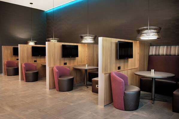 A modern lounge area with seating arrangements, tables, and built-in televisions.