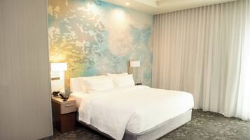 Een hotelkamer met een groot bed, een nachtkastje met een lamp, een telefoon en een muur met een camouflageprint.