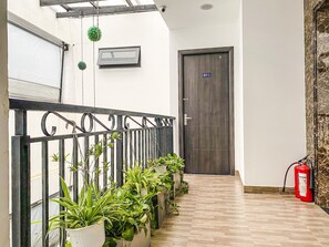 A hallway with a metal railing, potted plants, a fire extinguisher, and a door marked with the number 601. - Hometel & Apartment Dreamer (Ho Chi Minh City)