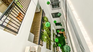 A narrow, multi-level corridor with balconies, green plants, and air conditioning units.