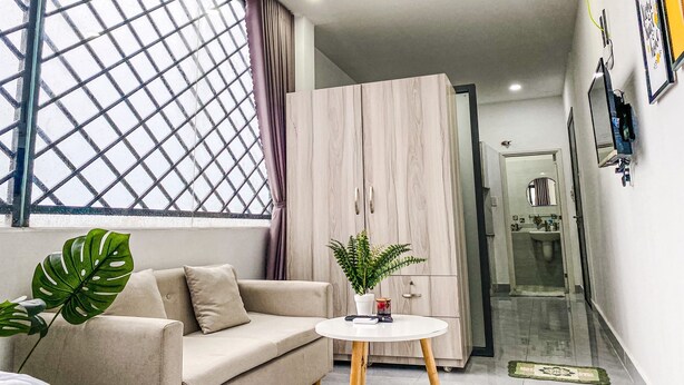 A modern living room with a sofa, a coffee table, and a large window with a grid pattern.