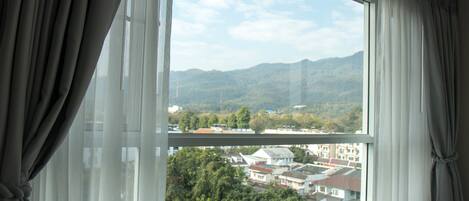 A window with a view of a residential area and mountains.