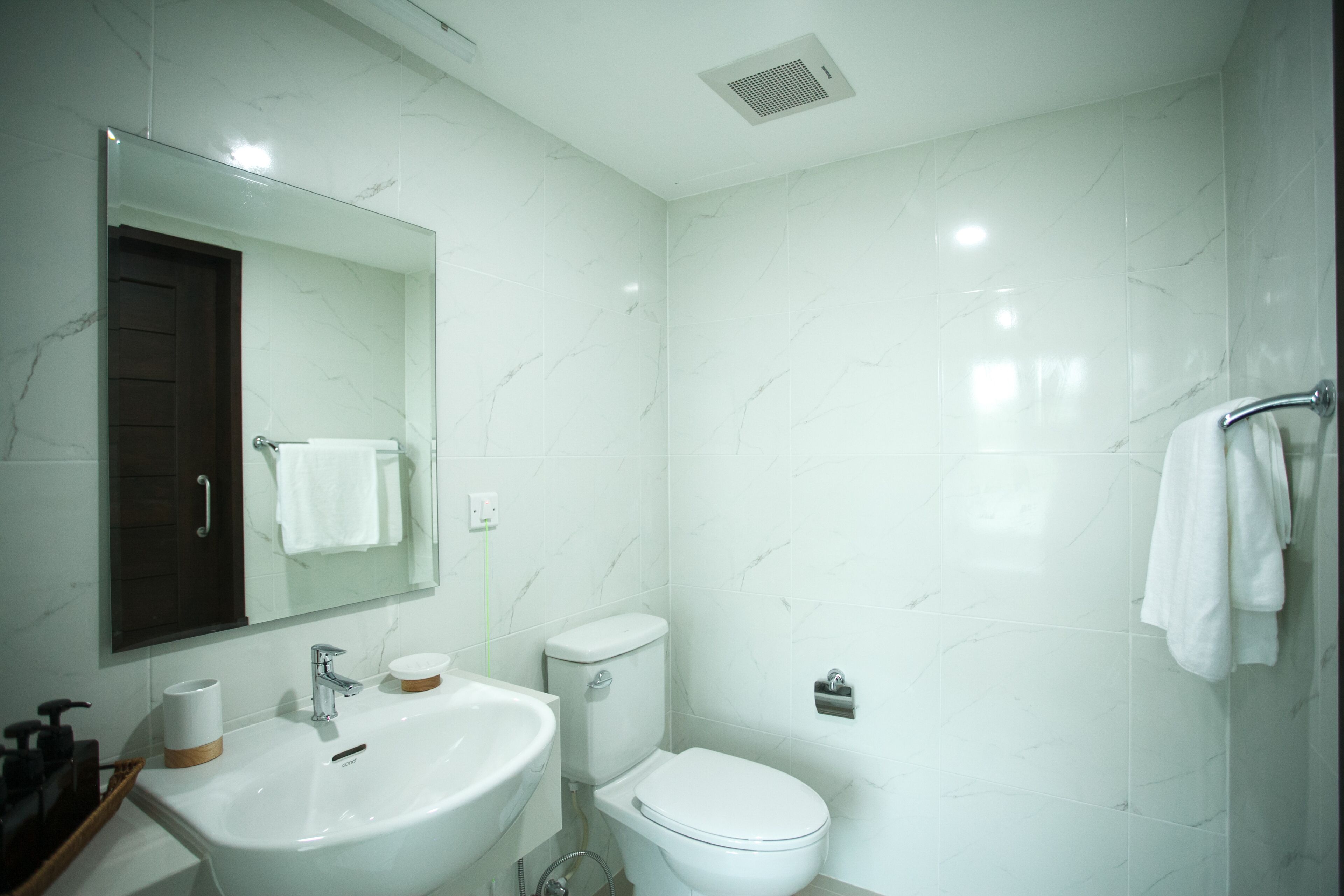 Een moderne badkamer met een wit wastafelmeubel, spiegel, toilet en handdoekhouder.