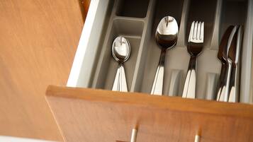 Un cajón con utensilios de cocina, como cuchara, tenedor y cuchillo.