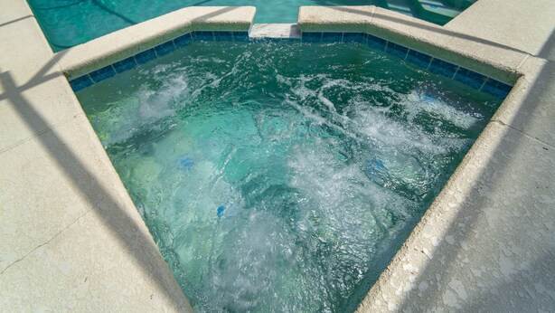 A hot tub with clear water and a tiled border. - Wooded View/Game Room/ Pool/Close to WDW (Davenport)