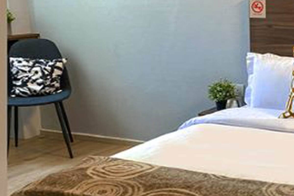 A hotel room with a bed, a chair, and a small plant.