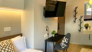 A hotel room with a bed, a desk, a chair, a television, and a small plant. - ST Signature Bugis Beach, DAYUSE, 5 hours: 4PM-9PM (Singapore)