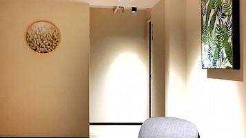 A modern interior with a grey upholstered chair, a round decorative wall piece, and a large abstract painting.