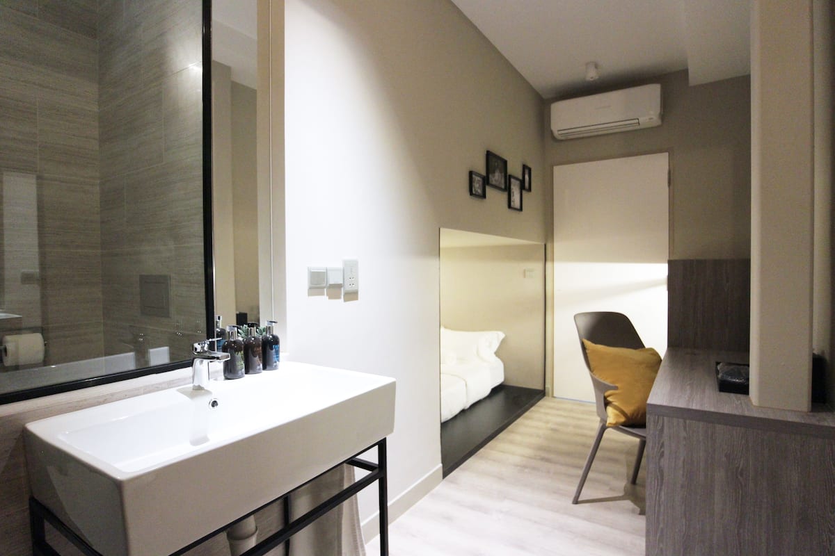 Uma casa de banho moderna com um espelho grande, lavatório branco e porta-toalhas.