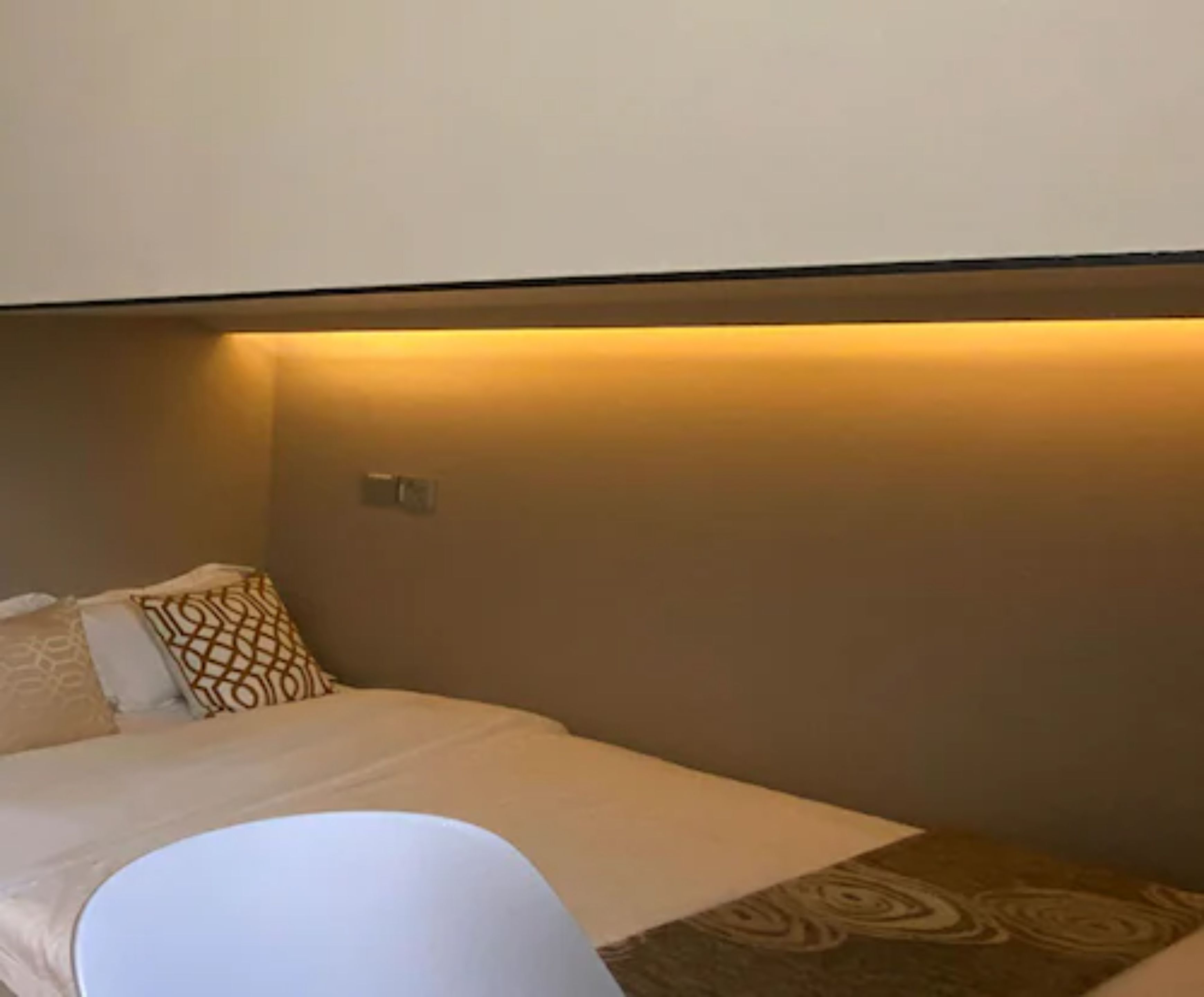 A hotel room with a bed, a bedside table, and a wall-mounted light fixture.