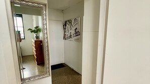 A hallway with a large mirror, a potted plant, and a wall-mounted artwork.