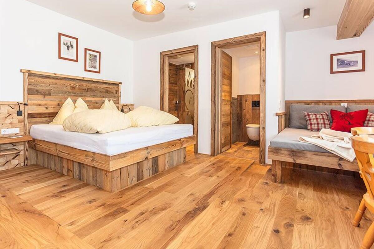 A room with a wooden bed, a sofa, and a wooden floor.