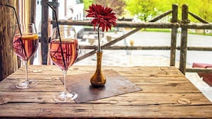 Une table en bois avec deux verres contenant une boisson rouge et un vase avec une fleur rouge.