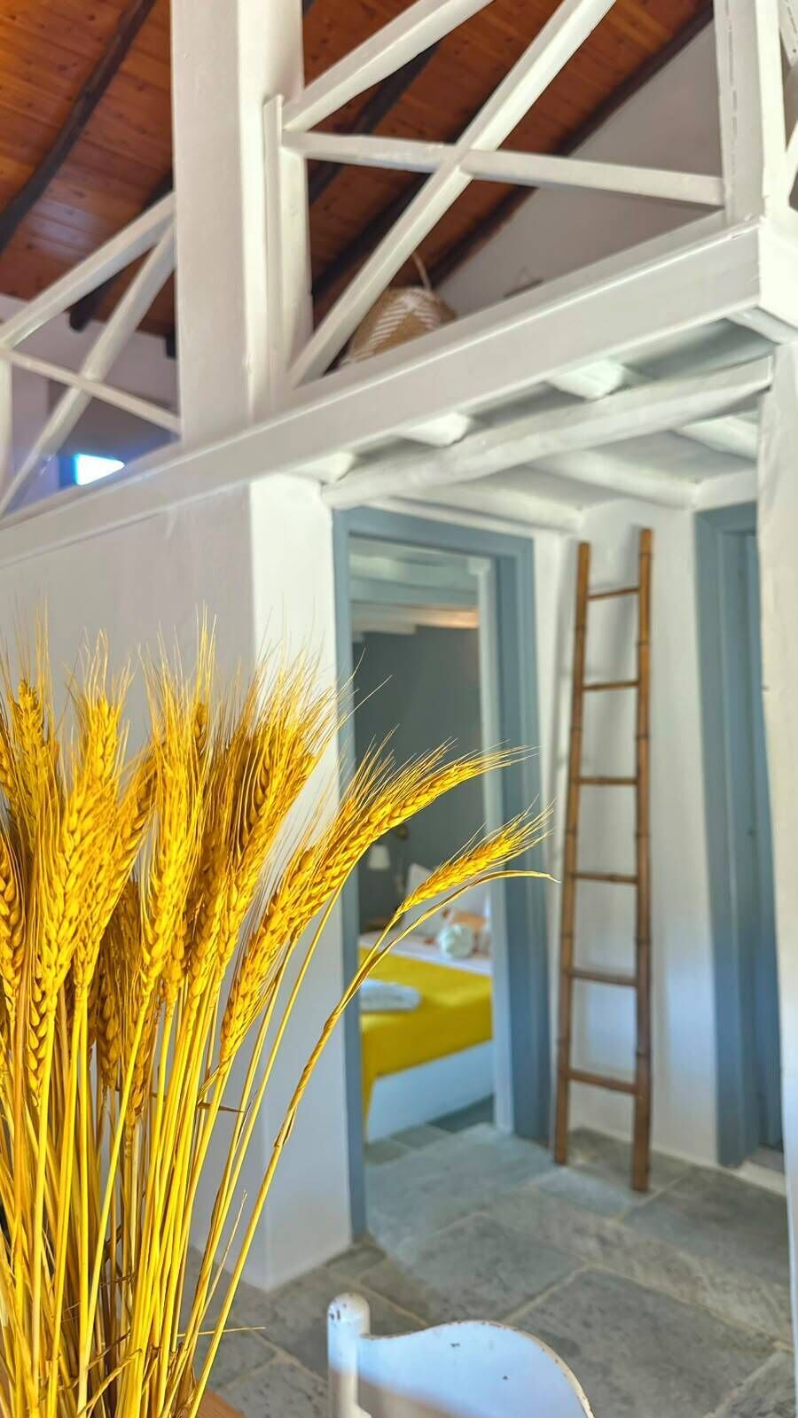 A room with a white ceiling, a wooden ladder, and a yellow chair.