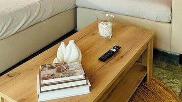 A living room with a sofa, a coffee table, a remote control, and a glass of ice cubes.