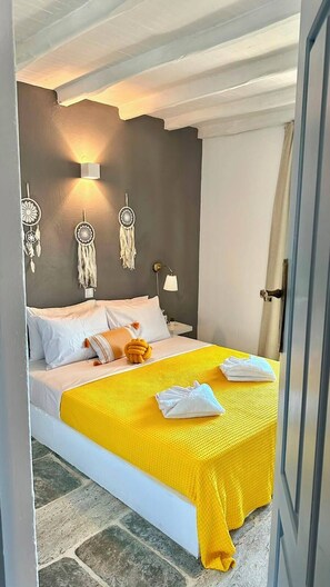A bed with a yellow bedspread, white pillows, and a white blanket. - PS House Platanias (Skiathos)