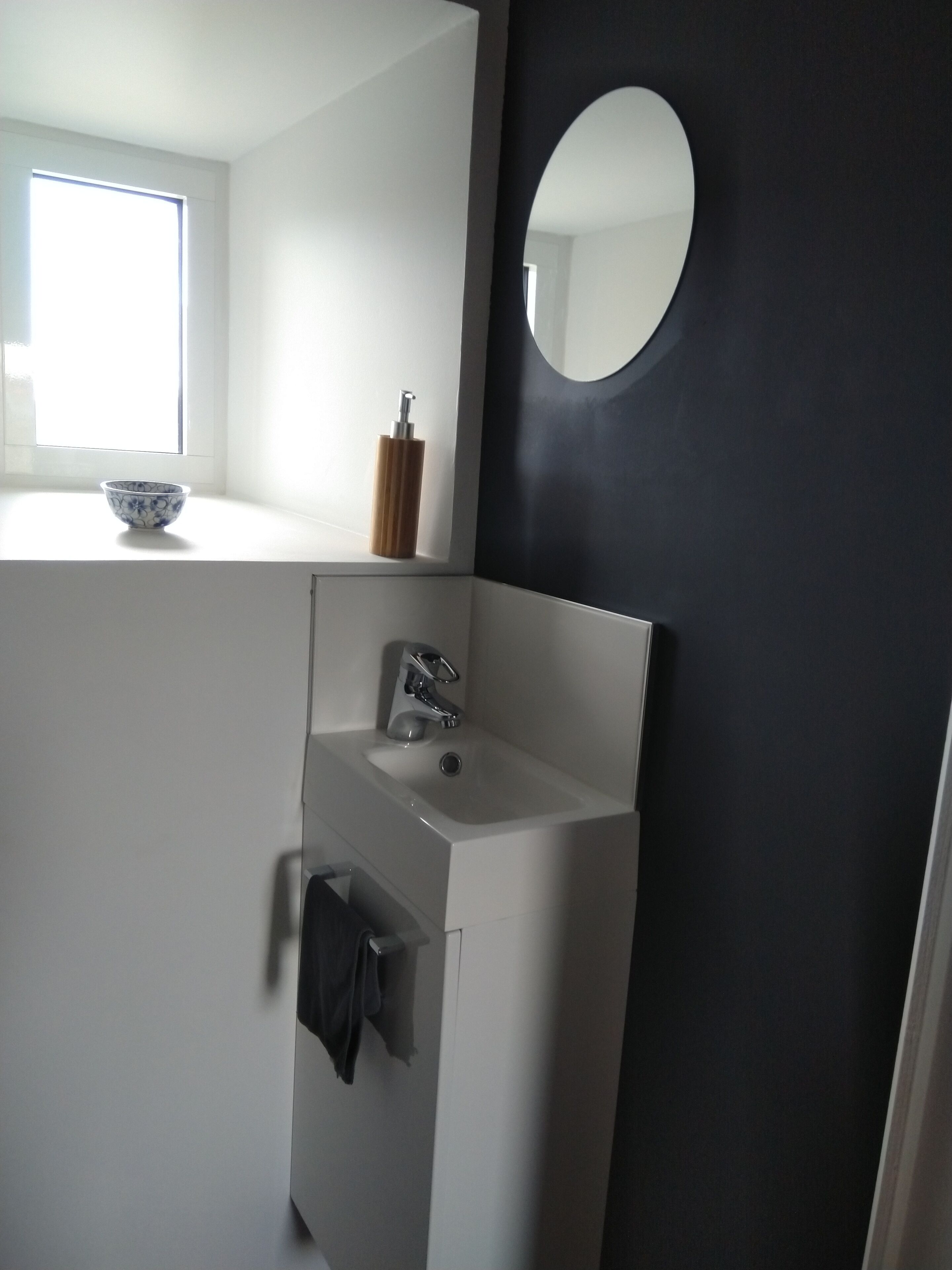 Une salle de bain moderne avec un lavabo blanc, un miroir et une fenêtre.