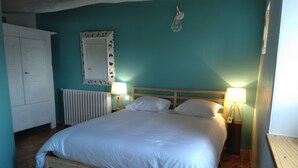 Et soveværelse med en træseng, hvidt sengetøj, en hvid radiator, et hvidt klædeskab og to sengeborde med lamper.