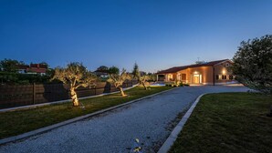 A modern house with a gravel driveway, a swimming pool, and a well-maintained lawn.