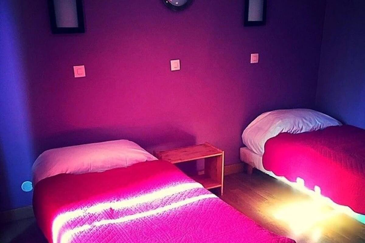A room with two beds, a nightstand, and a wall clock.