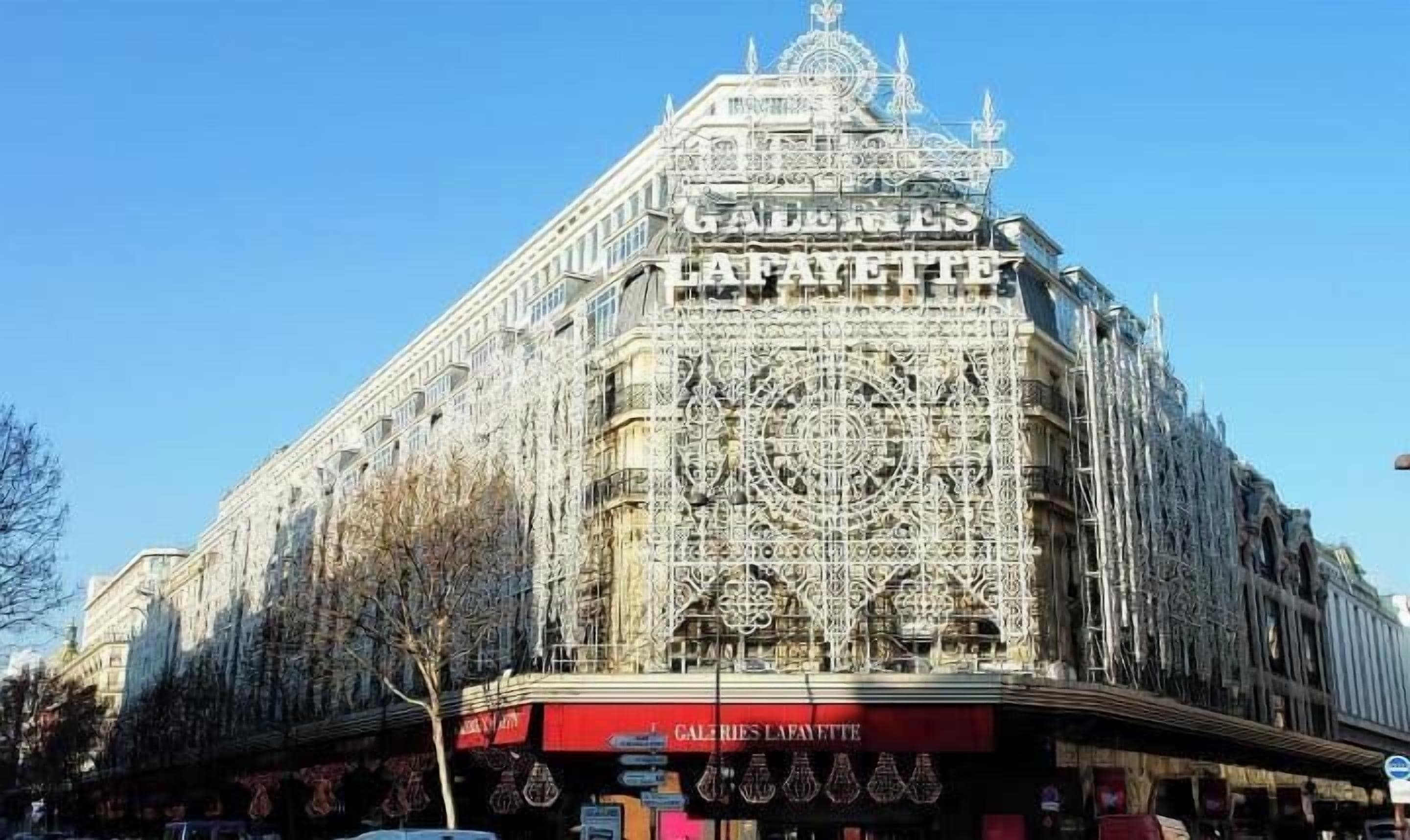 Een historisch gebouw met versierde architectuur en een opvallend bord met 'Galeries Lafayette'.