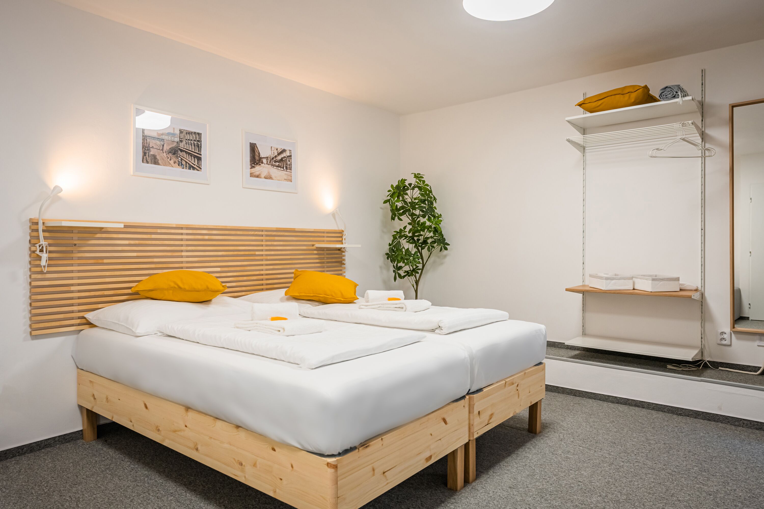 A modern bedroom with a wooden bed, white linens, and a small plant.