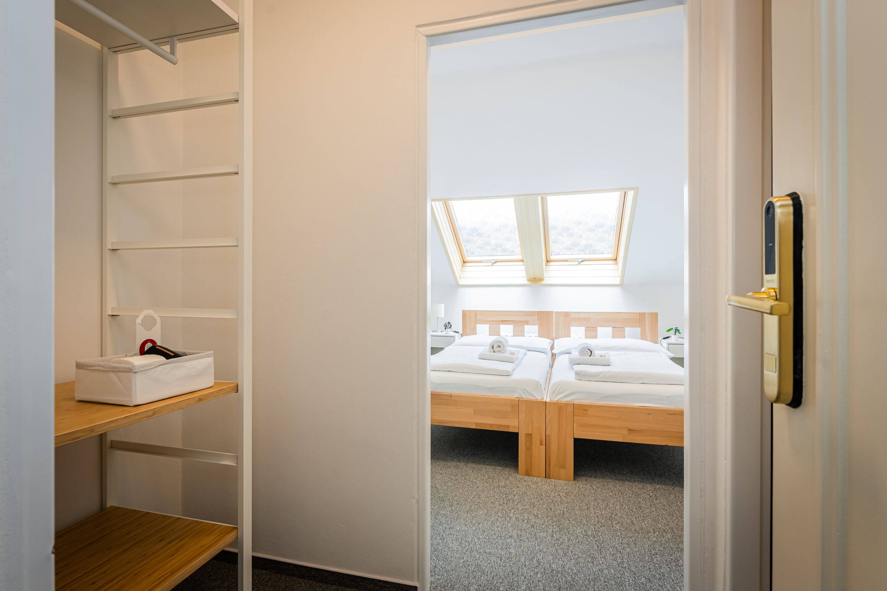 Une chambre avec une lucarne, un lit en bois et une armoire avec des étagères.