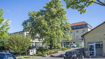 A building with a modern design, a parking area, and a tree in front.