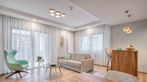 Una sala de estar moderna con un sofá, un sillón verde, una mesa de centro de madera y una mesa de comedor.