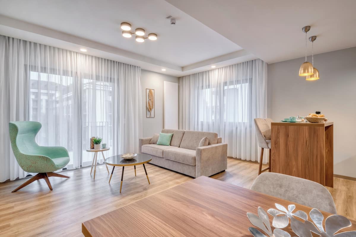Una sala de estar moderna con un sofá, un sillón verde, una mesa de centro de madera y una mesa de comedor.