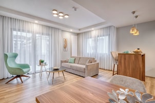 Una sala de estar moderna con un sofá, un sillón verde, una mesa de centro de madera y una mesa de comedor.