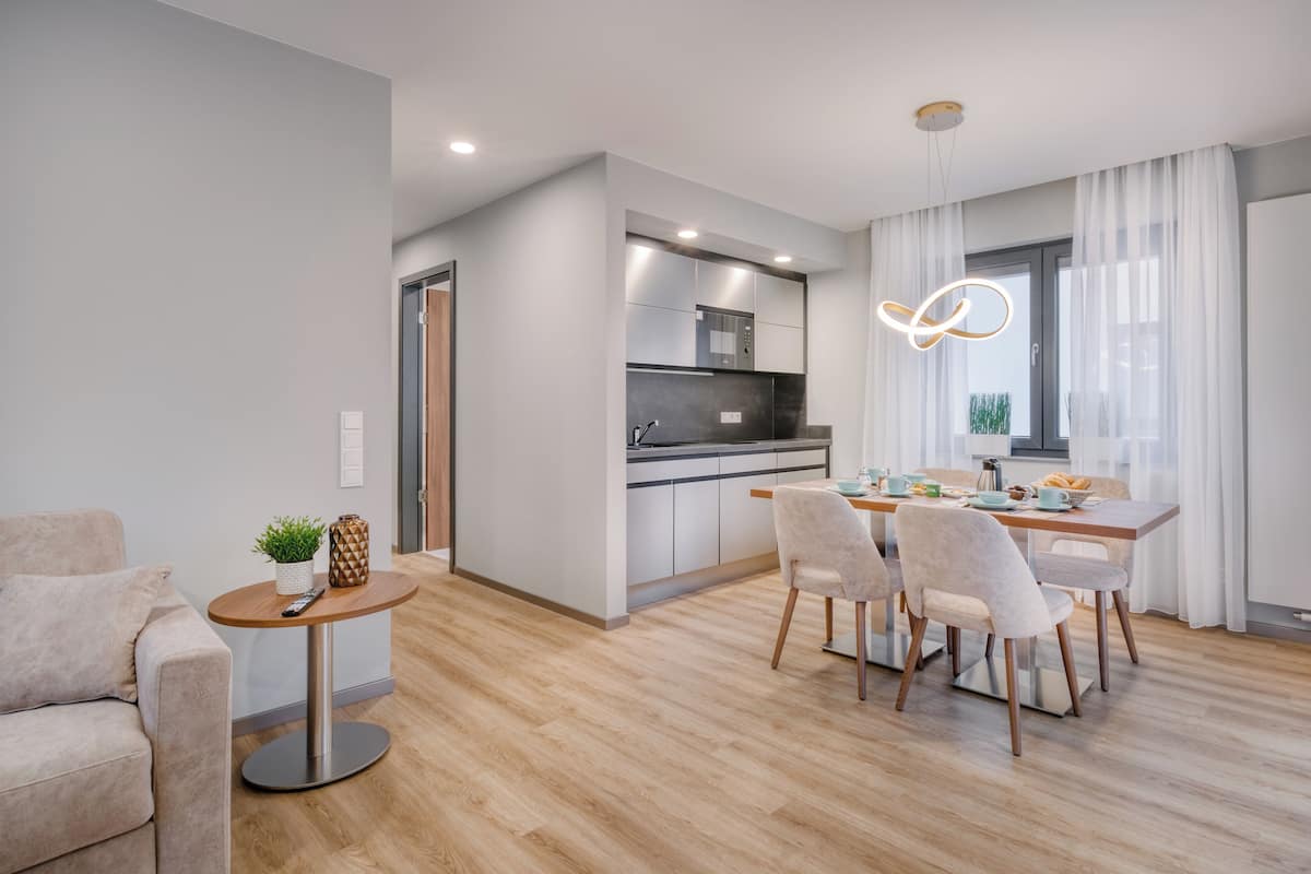 Una cocina moderna con comedor, piso de madera y una lámpara colgante.