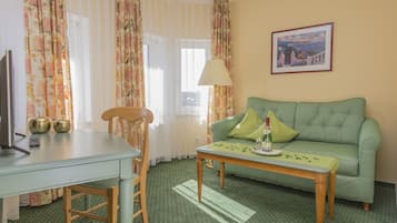 Una habitación con un sofá verde, una mesa de madera, una silla, un televisor y una lámpara.