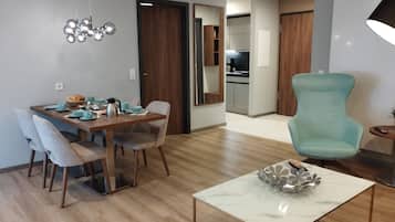 A modern living room with a dining area, a kitchen in the background, and a teal armchair.