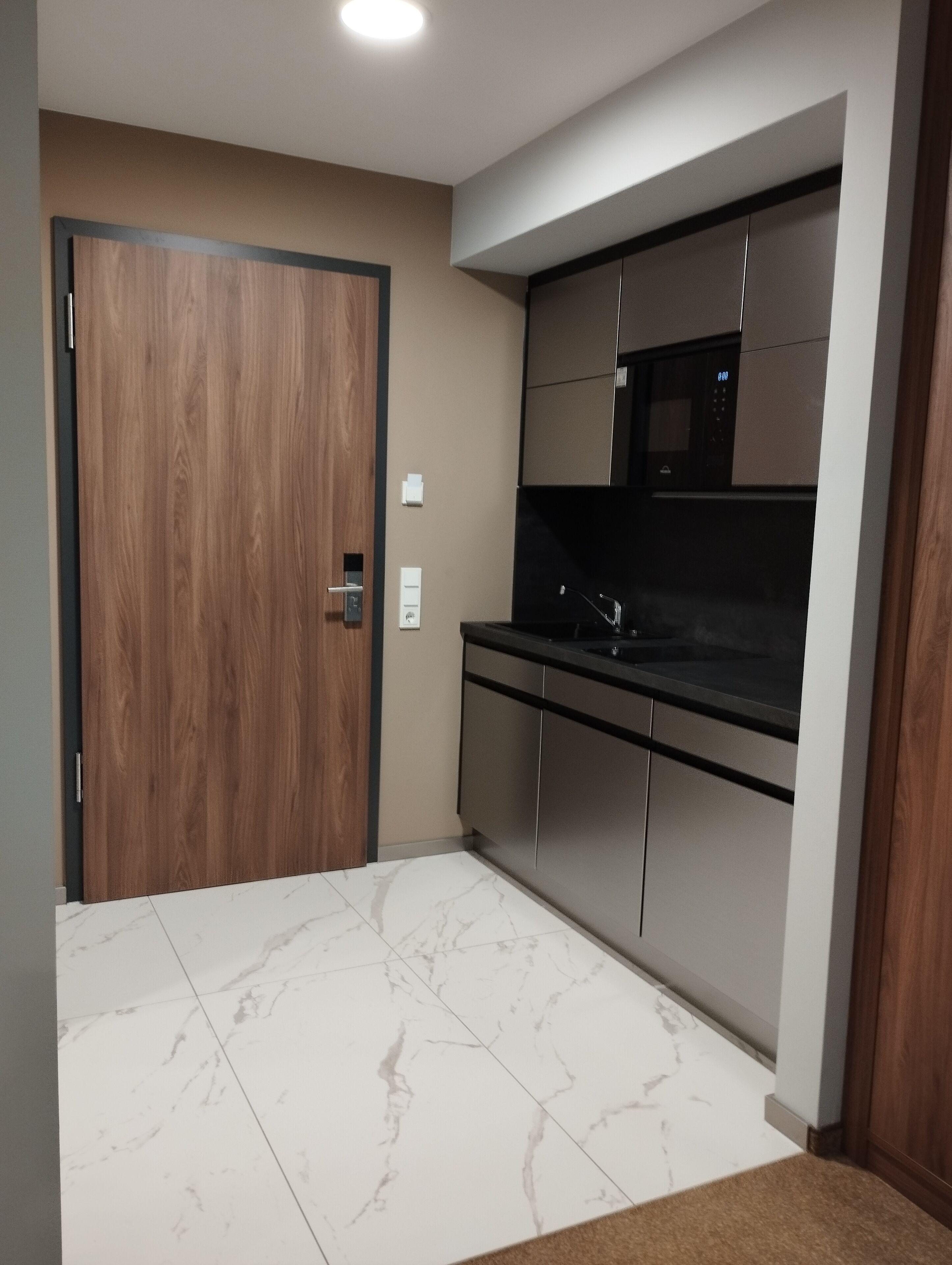 Eine moderne Küche mit Holztür, Edelstahlgeräten und Marmorböden.