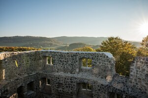 Una antigua estructura de piedra con ventanas arqueadas y vistas a colinas ondulantes al fondo.