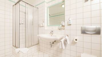 A bathroom with a glass-enclosed shower, a sink with a mirror above it, and a toilet.