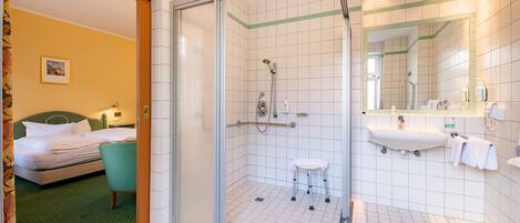 A hotel bathroom with a shower, sink, and toilet.