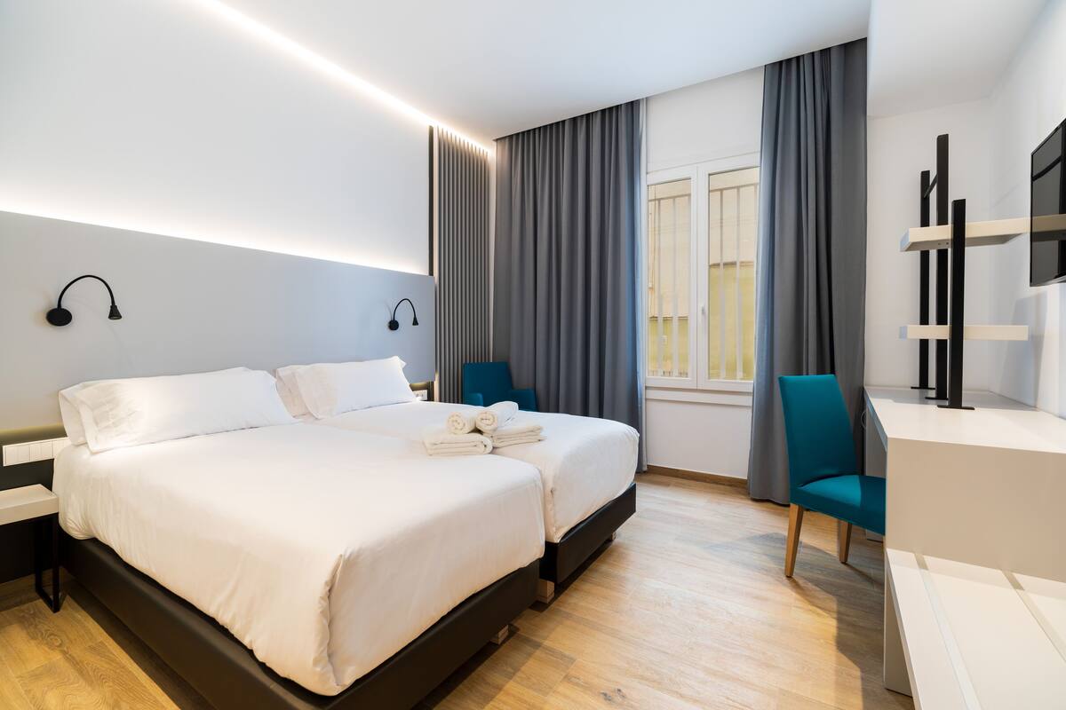A modern hotel room with a large bed, a desk, and a chair.