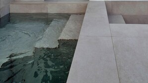 Um edifício moderno com porta de vidro e uma pequena área de piscina.