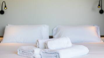 A neatly made bed with white linens and folded towels.