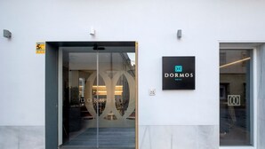A entrada de um hotel com porta de vidro e placa exibindo o nome do hotel.