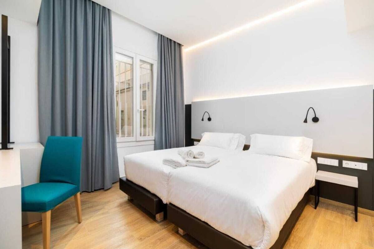 A modern hotel room with a large bed, a desk, and a chair.