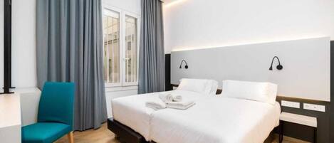 Una habitación de hotel moderna con una cama grande, un escritorio y una silla.