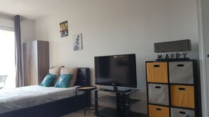 Un dormitorio con una cama, televisión, escritorio y armario.
